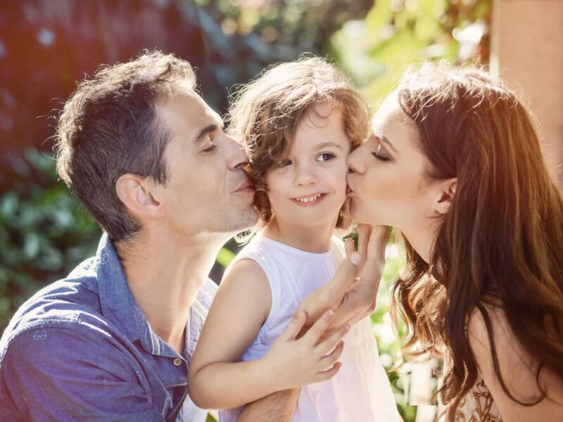 Parents kissing their child